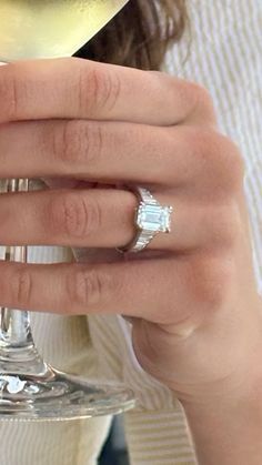 a woman holding a wine glass with a diamond ring on it