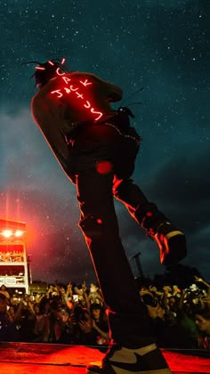 a man standing on top of a skateboard in front of a crowd at night