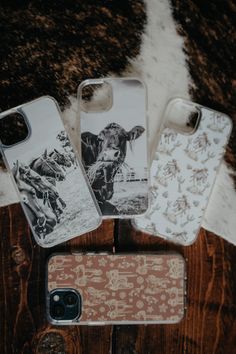 three cell phones sitting next to each other on top of a cow skin rug with an image of a cowboy