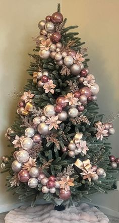 a small christmas tree with ornaments on it's top and pink balls hanging from the branches