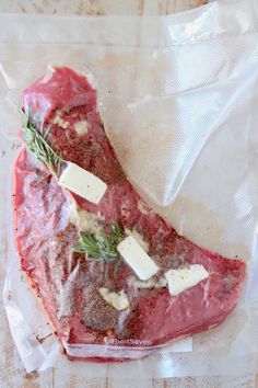 a piece of meat sitting on top of a plastic bag covered in cheese and herbs