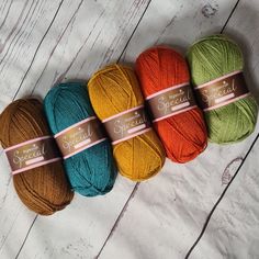 three skeins of yarn sitting on top of a white wooden floor next to each other