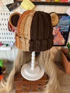 there is a knitted bear hat on top of a doll's head with long blonde hair