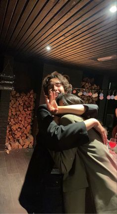 two people hugging each other while standing in front of a fire place