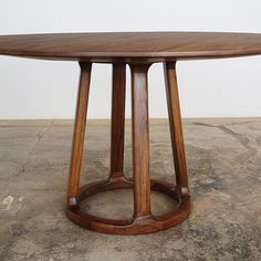 a round wooden table sitting on top of a cement floor