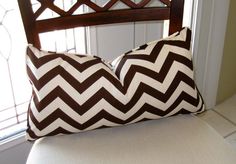 a brown and white pillow sitting on top of a wooden chair next to a window