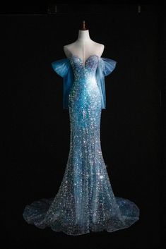 a dress on display in the dark with blue sequins and bows around it