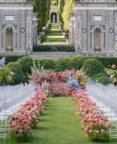 an outdoor ceremony setup with white chairs and pink flowers on the aisle, surrounded by greenery