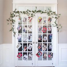 a white double door decorated with christmas cards and greenery, hanging from the side