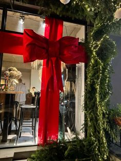 a large red bow tied to the side of a building with christmas decorations around it