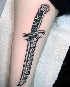 a black and white tattoo with a knife on the arm that has an intricate design