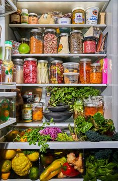 an open refrigerator filled with lots of different types of vegetables and food in it's shelves