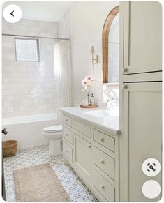 a bathroom with white fixtures and tile flooring, along with a rug on the floor