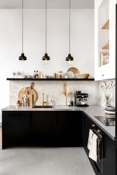 a black and white kitchen with hanging lights above the countertop, pots and pans on the shelves