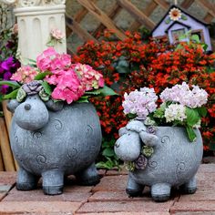 two ceramic sheep planters with flowers in them