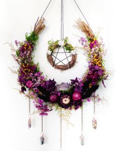 a wreath with flowers hanging from it's side on a white wall next to other decorations