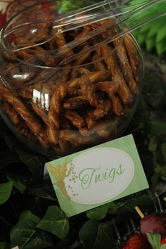 there is a glass bowl filled with pretzels on top of some green leaves