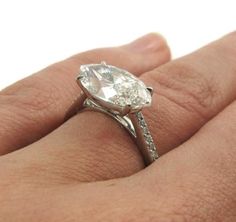 a woman's hand with a diamond ring on top of her finger and an engagement band