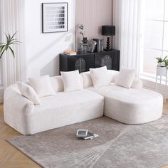 a large white couch sitting on top of a rug in a living room next to a window