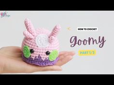 a hand holding a small crocheted toy with the words goony on it