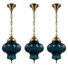 three blue glass lamps hanging from chains on a white background, one is gold and the other two are green