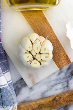 garlic on a cutting board next to a bottle of olive oil