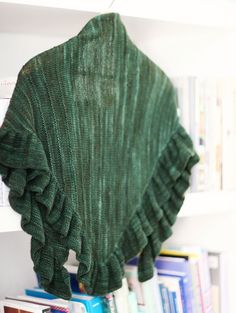 a green scarf hanging from the side of a bookshelf