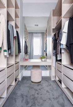 a walk in closet filled with lots of drawers and clothes on top of shelves next to a window