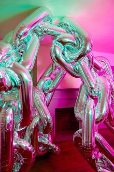 an inflatable balloon sculpture is displayed on a wooden floor next to a pink wall