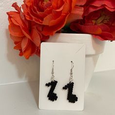 a pair of black and white earrings sitting on top of a table next to a flower