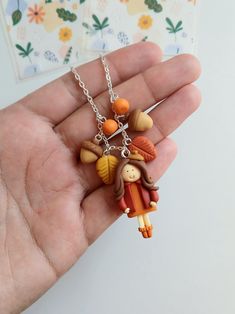 a hand holding a small necklace with charms on it's sides and an image of two children hanging from the back