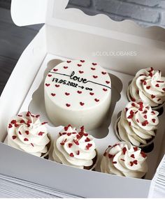 cupcakes with white frosting and red sprinkles in a box