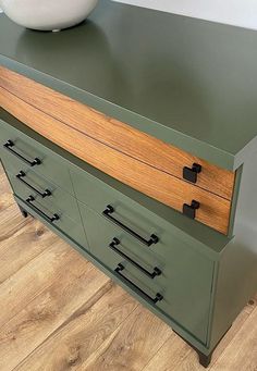 a green dresser with drawers and a bowl on top