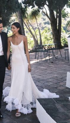 a man and woman are walking down the street holding hands while dressed in formal attire