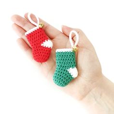 a hand holding two small crocheted christmas stockings