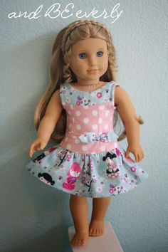 a doll with blonde hair wearing a pink and blue dress on top of a white shelf