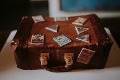 a brown suitcase with stickers on it sitting on top of a white tablecloth