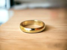 a gold wedding ring sitting on top of a wooden table