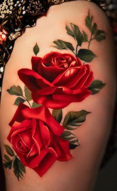 a close up of a woman's thigh with red roses on the side and green leaves