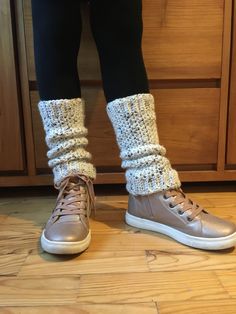 a person standing on top of a wooden floor next to a pair of gray shoes