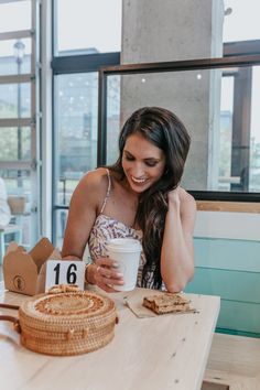 a woman sitting at a table holding a cup