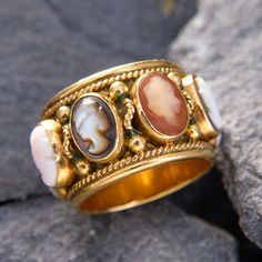 a gold ring with two stone cabs on it sitting on top of a rock