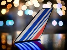 a blue and red striped airplane sitting on top of a table next to a blurry background