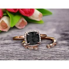 a black diamond ring sitting on top of a wooden table next to pink tulips