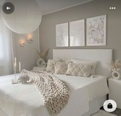 a white bed sitting in a bedroom next to two lamps and pictures on the wall