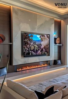 a living room with a large television mounted on the wall and a fire place in front of it