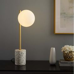 Bring intrigue into your home ambient lighting with the Logic Tall Terrazzo Table Lamp in your bedroom, living room, office, entryway, or study. This side table lamp dispenses a tranquil aura complementing mid-century modern, contemporary, or eclectic decors. A captivating coffee table lamp, Logic illuminates with an opaque glass globe lampshade set vertically on a satin brass rod rising from a smooth terrazzo cylinder base. This sculpted living room lamp, with a black power cord and a convenien Mid Century Modern Table Lamp, Globe Lampshade, Terrazzo Table, Side Table Lamp, Coffee Table Lamp, Brass Rod, Living Room Lamp, Office Entryway, Mid Century Modern Table