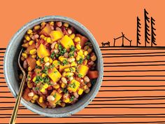 a bowl filled with beans and corn on top of a table next to an orange wall