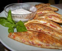 some food that is on a plate with sauce and spinach leaves next to it