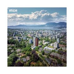 an aerial view of a city with mountains in the background and blue skies above it